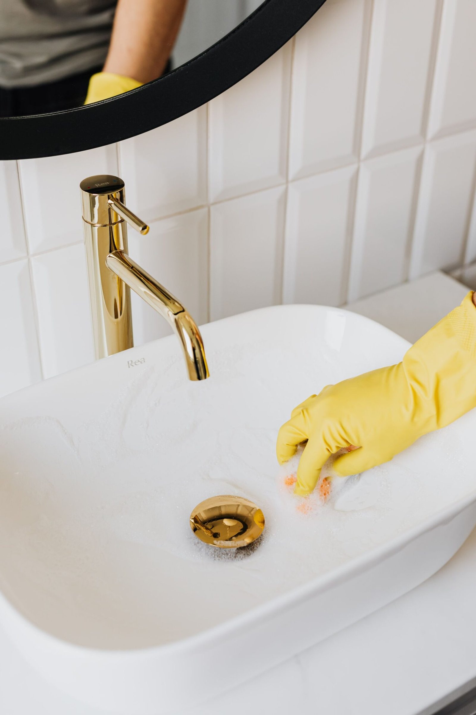 From above anonymous housekeeper in yellow rubber gloves wiping b