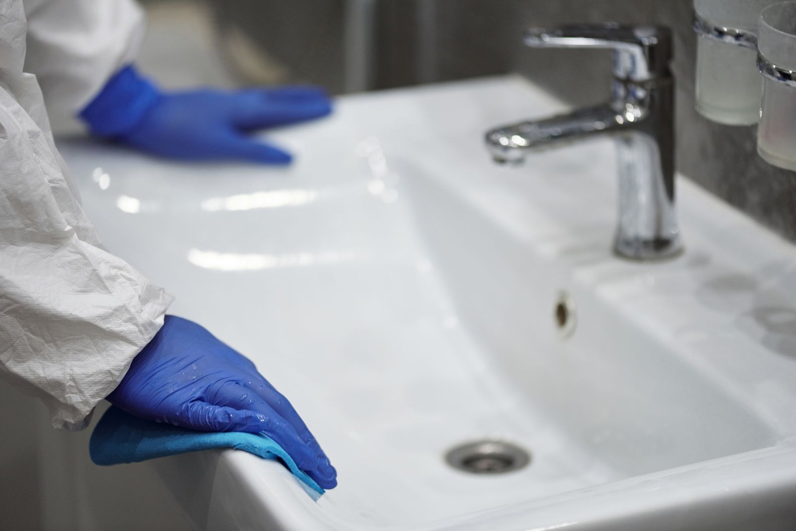 Close-up of a gloved professional cleaning a sink for sanitation.
