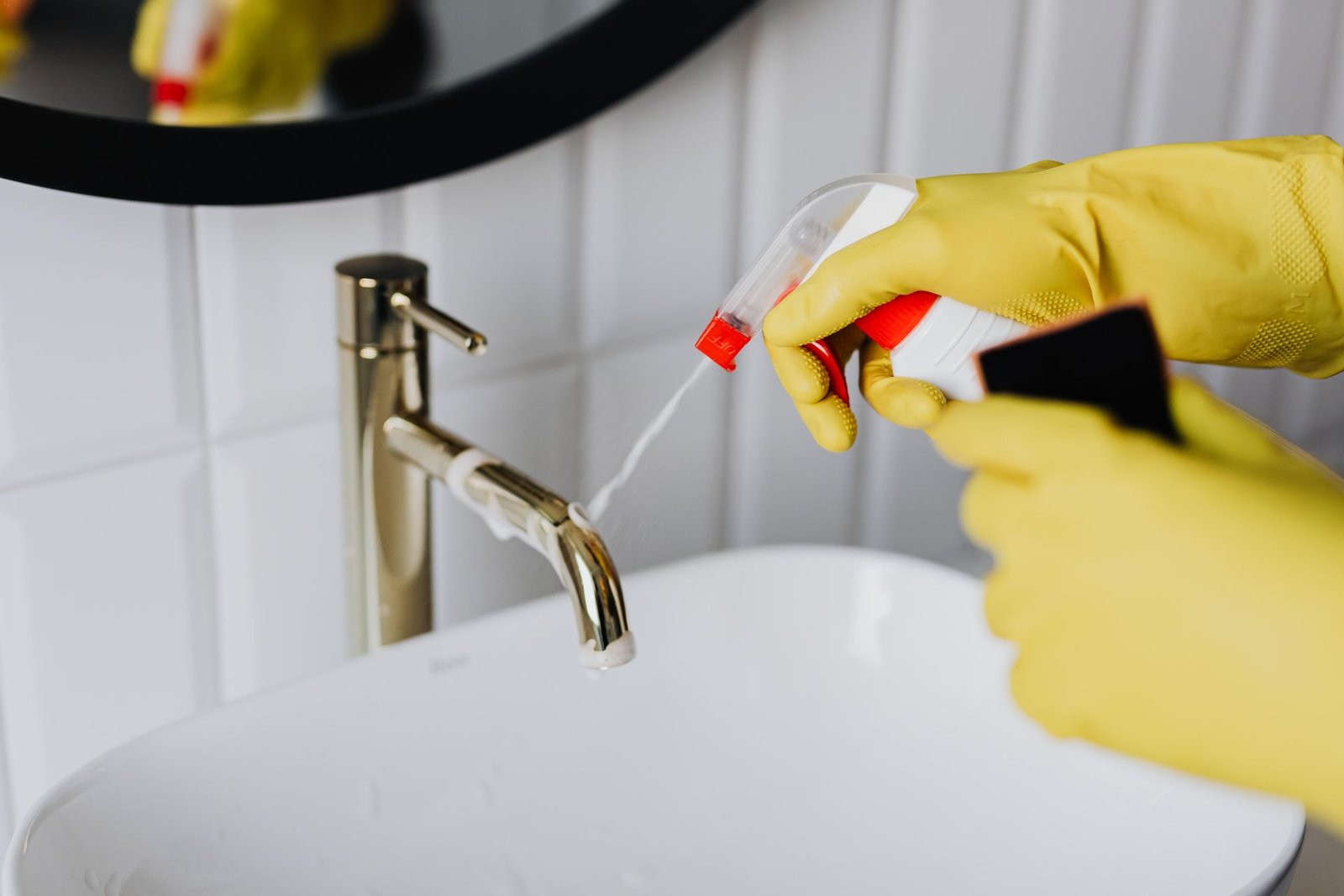 From above anonymous housekeeper in yellow rubber gloves spraying