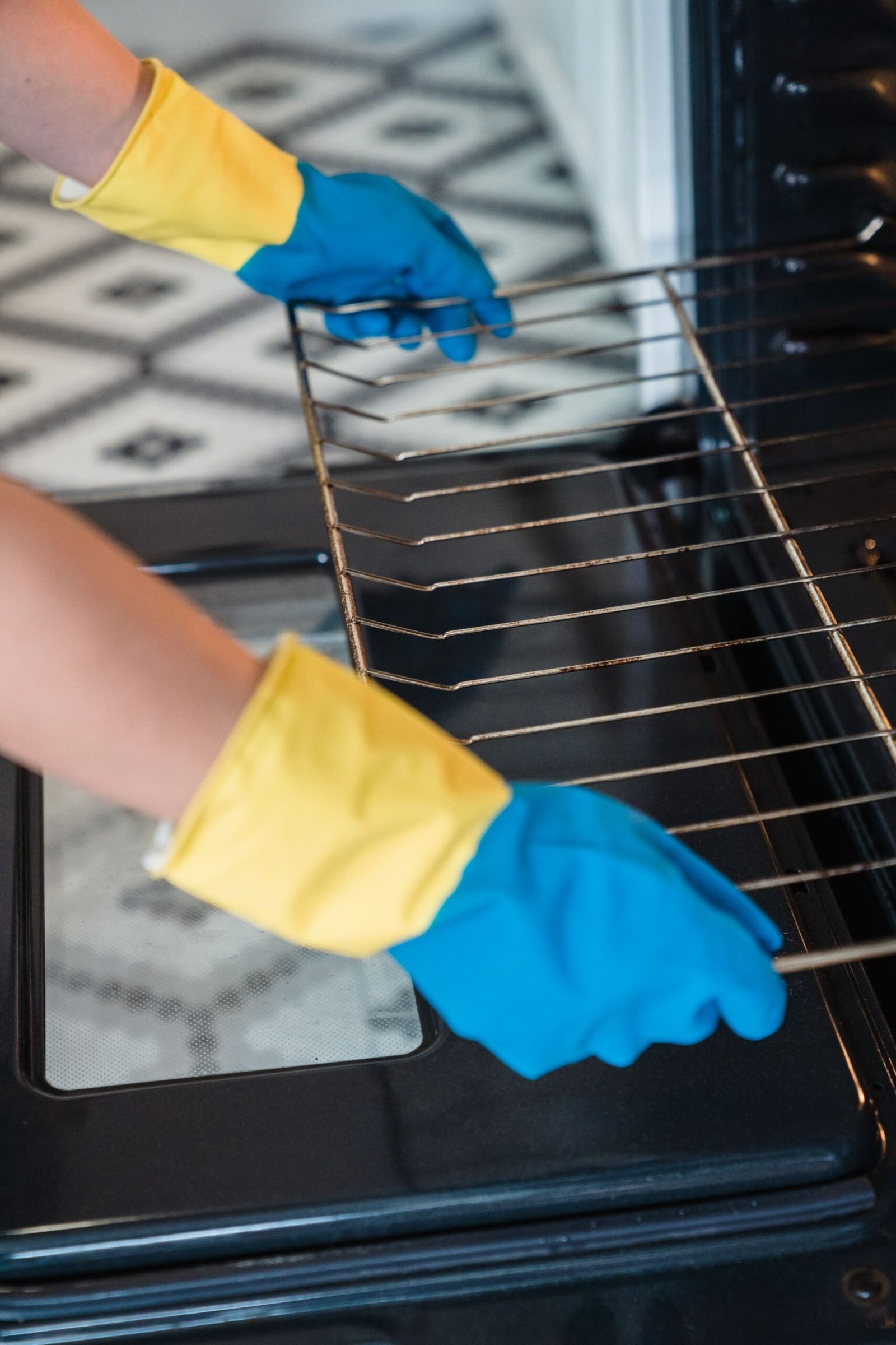 Person wearing gloves cleaning an oven, focusing on hygiene and h