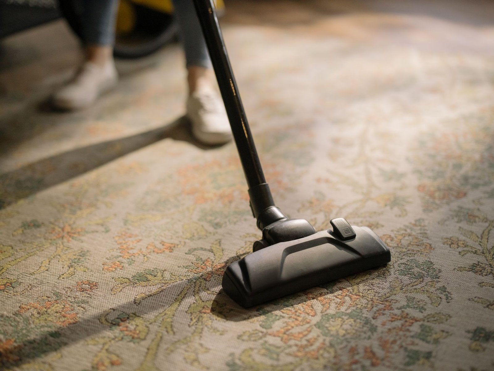 Close-up of a vacuum cleaner on a patterned carpet in a sunlit ro