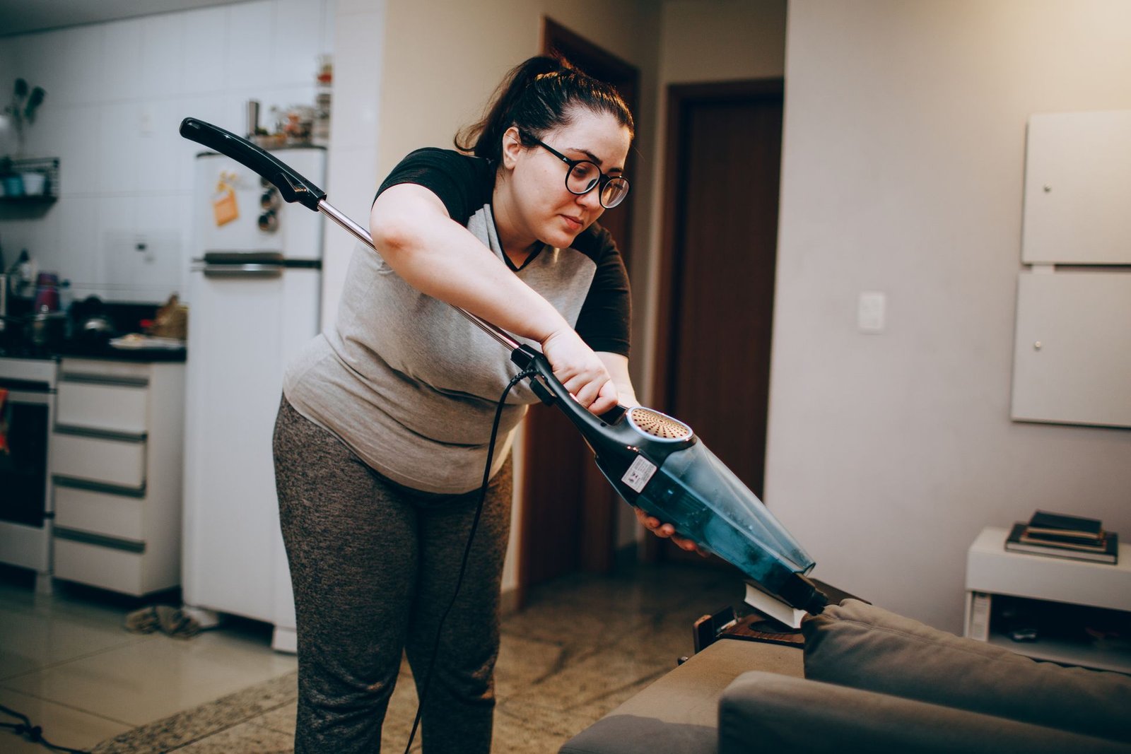 A woman vacuuming a couch in a cozy living room setting, emphasiz