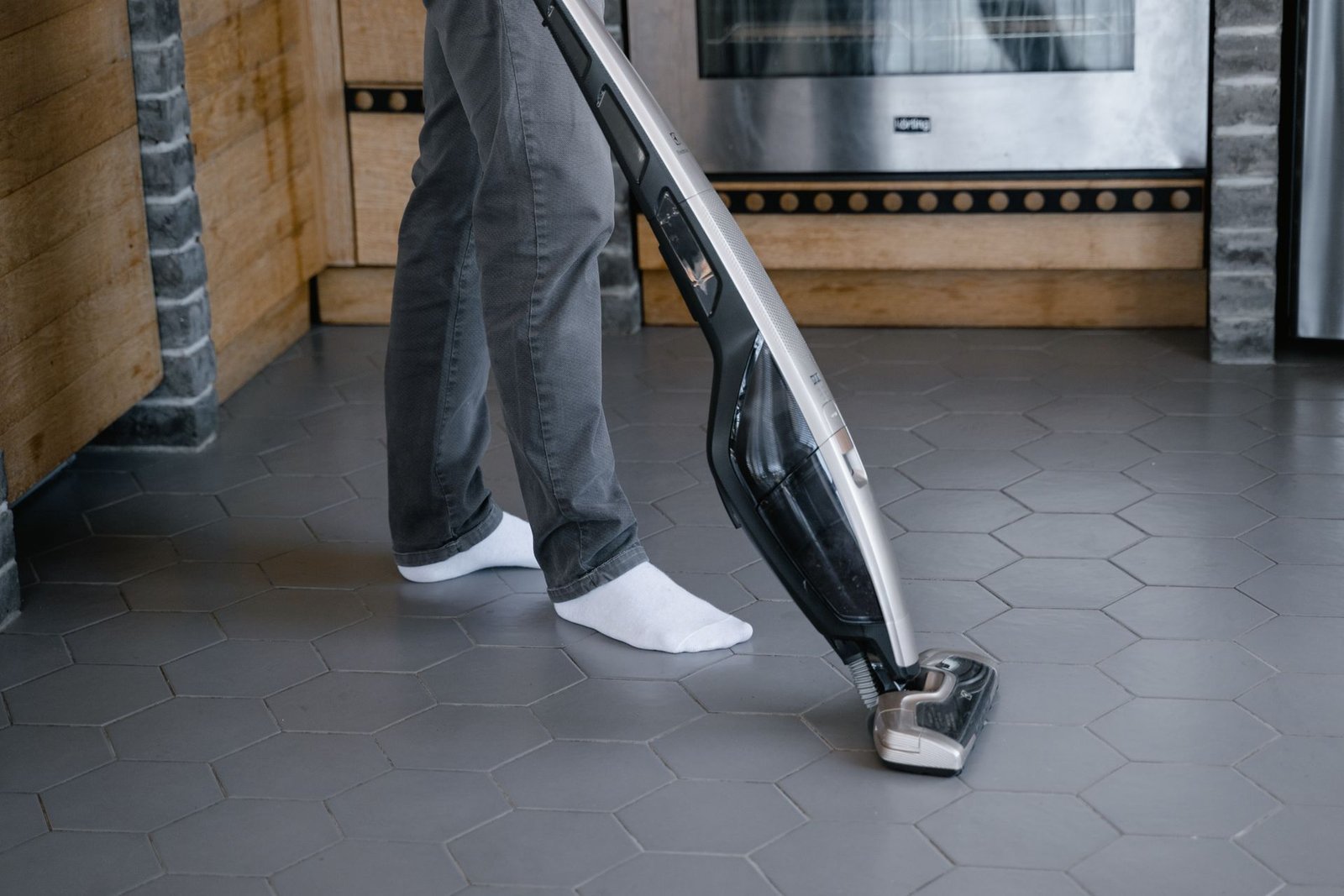 A person cleaning a tiled floor with a modern vacuum cleaner indo