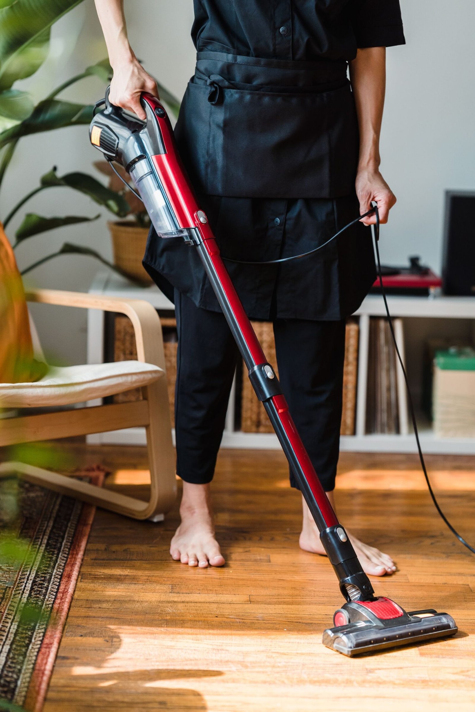 A person vacuuming a wooden floor in a cozy living room setting i