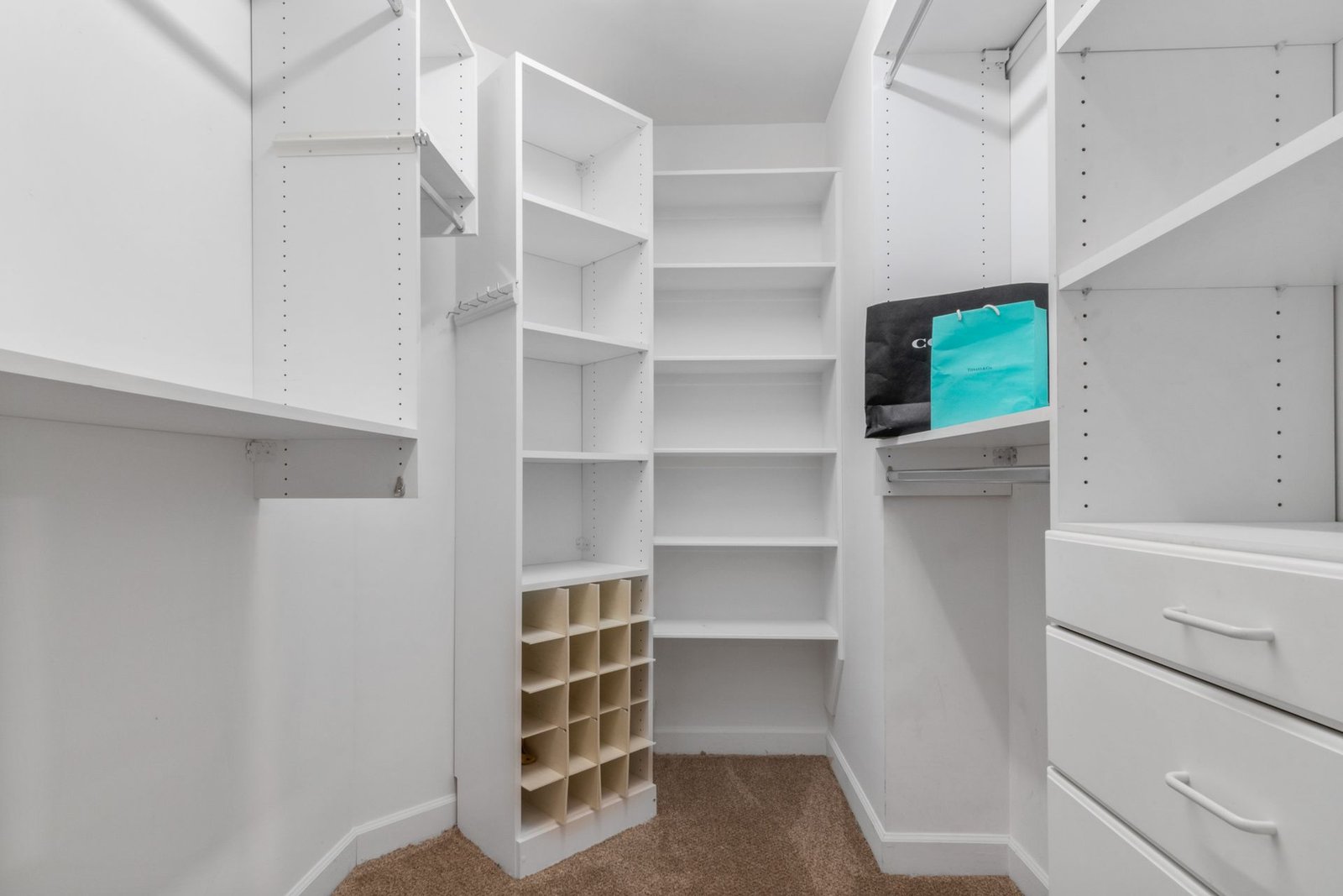 Explore a spacious white closet interior featuring shelves, drawe