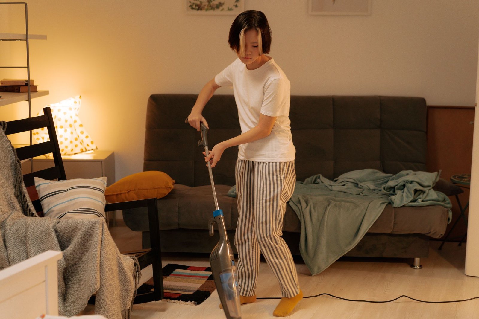 Asian woman cleaning a messy living room at home with a vacuum cl
