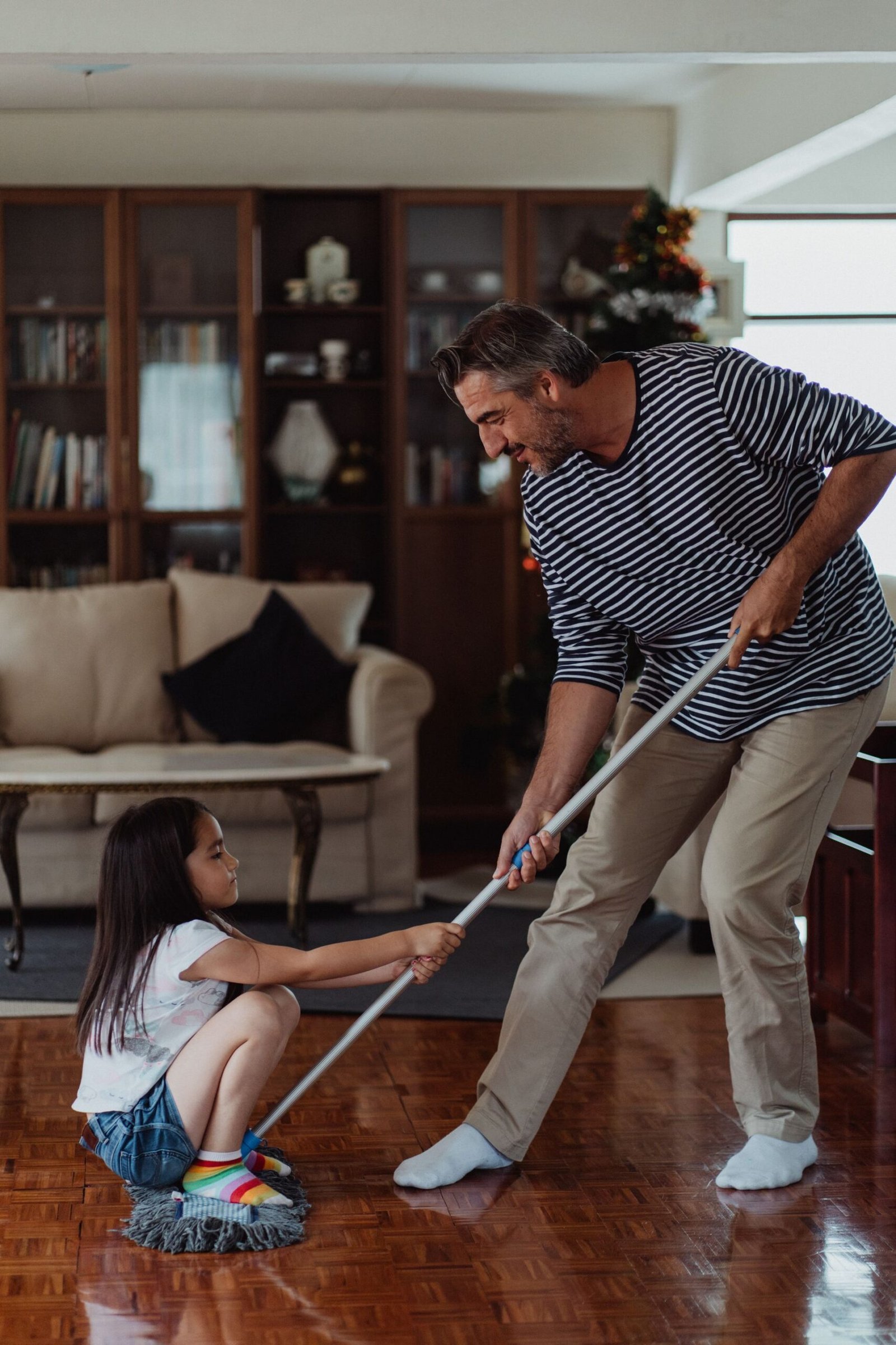 A father and daughter enjoying mopping the floor in the living ro