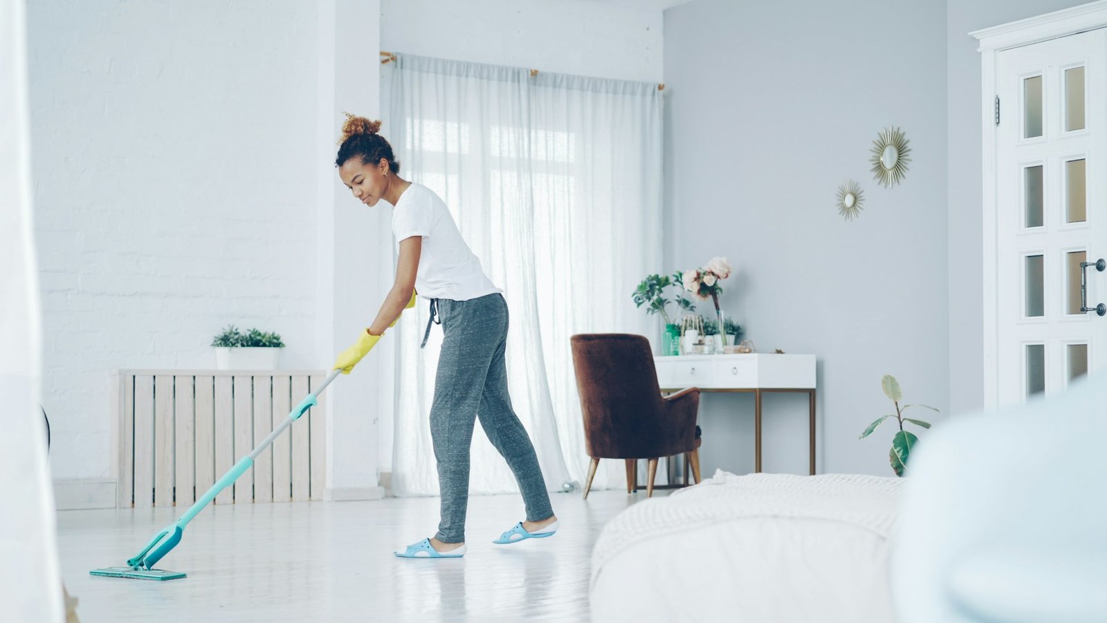 A woman mops a bright, modern living room floor