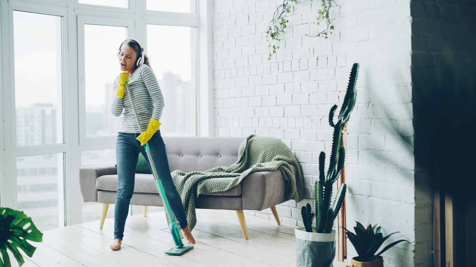 Woman with headphones cleaning and dancing