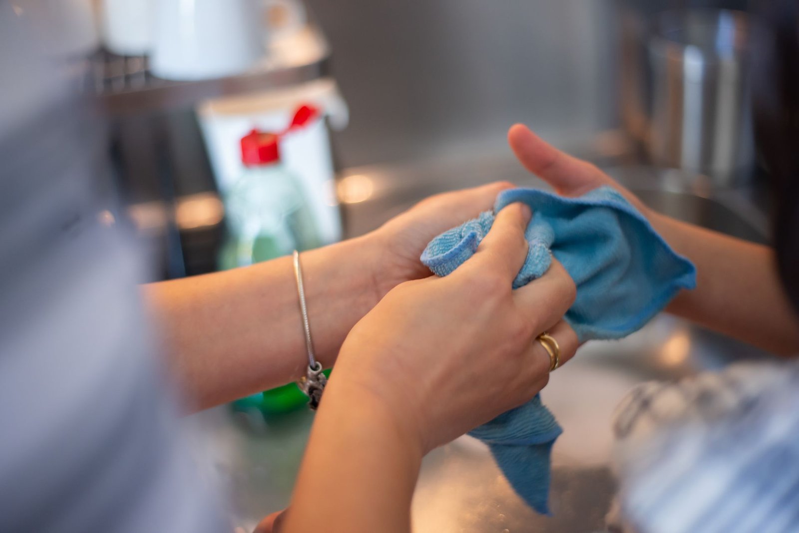 Detailed image of two people cleaning using a blue cloth indoors.