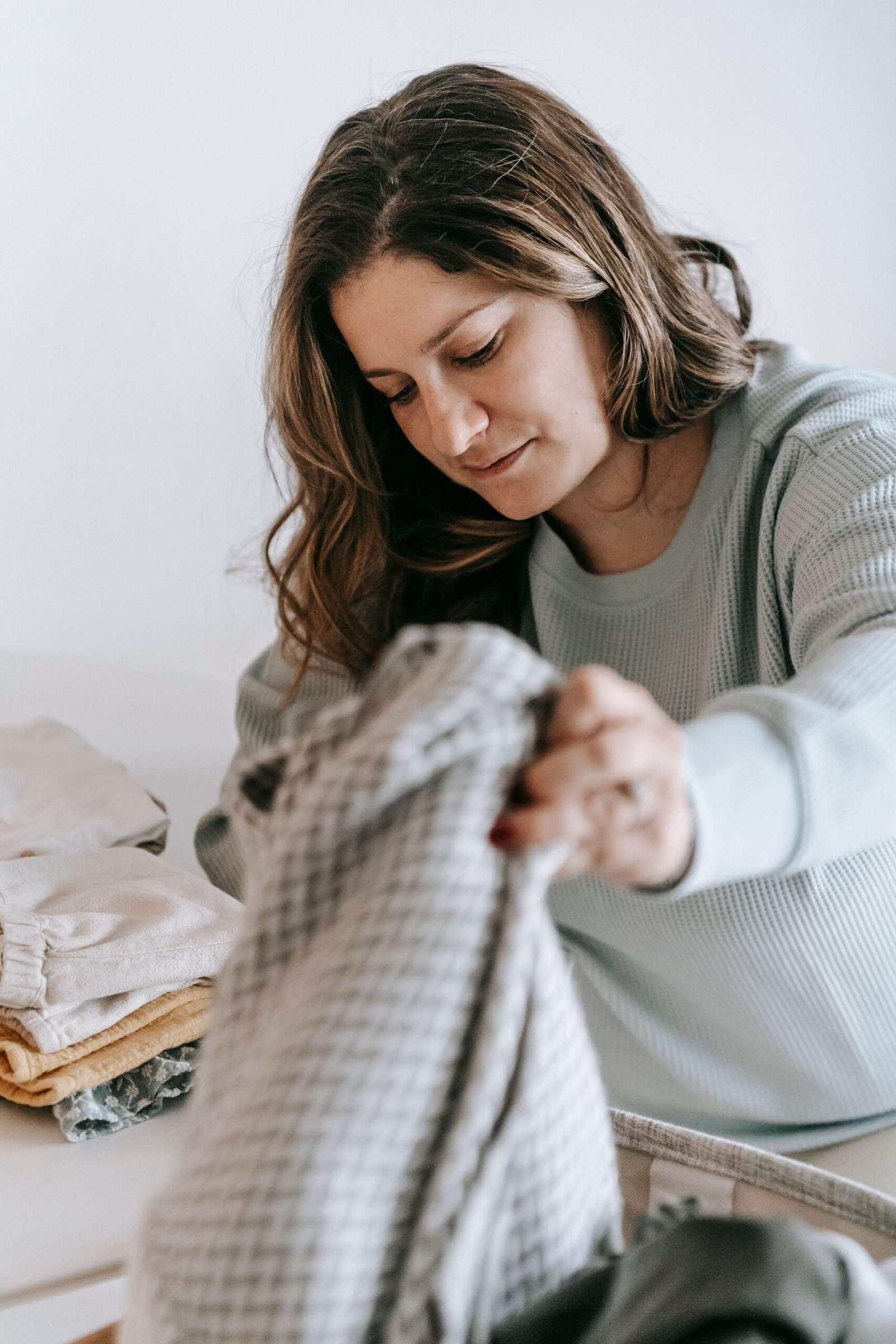 Focused female putting out clean clothes from bag while sitting a