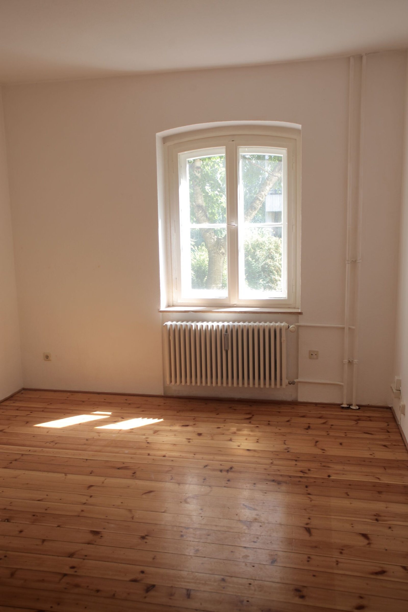 Spacious empty room with wooden floor and large window in Berlin,