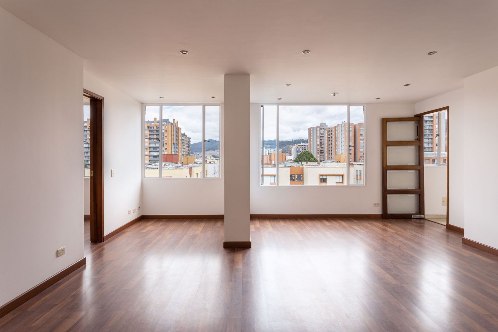 An empty, bright apartment interior showcasing wide windows and w