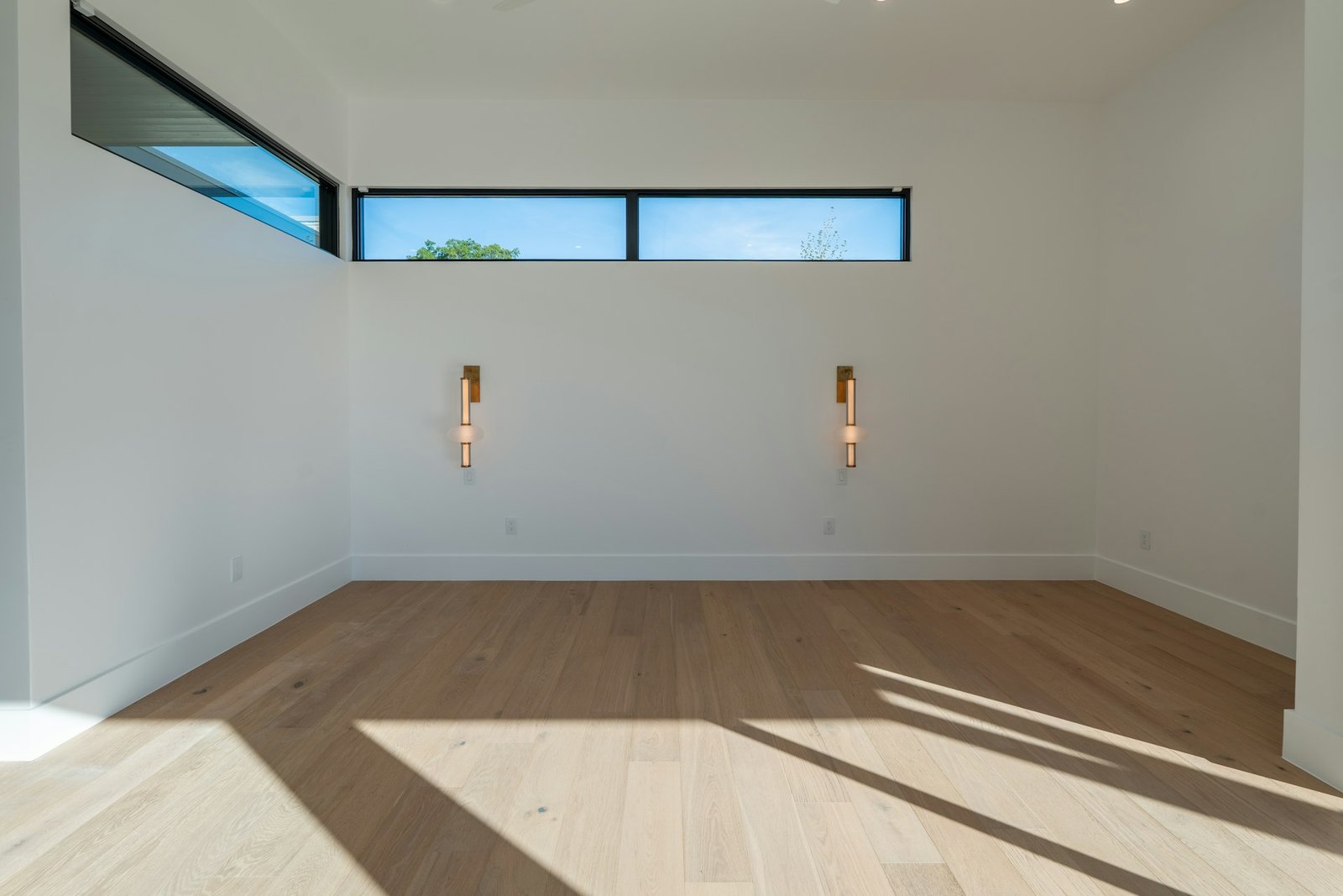 Empty room with white walls, hardwood floor, and high windows