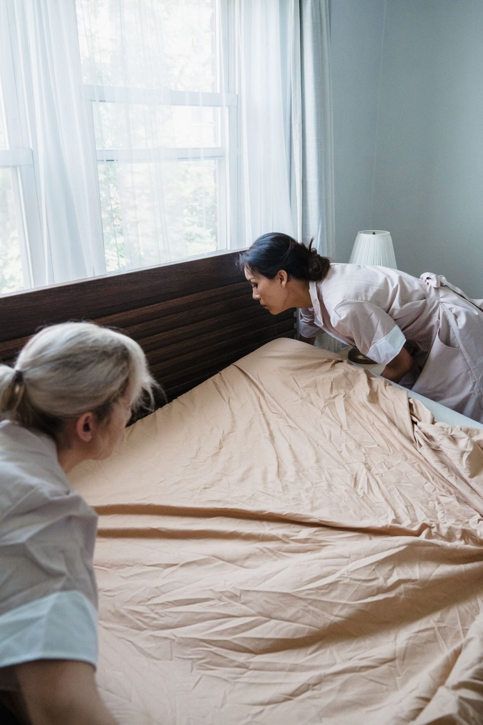 Hotel maids changing bed linens, showcasing professional housekee