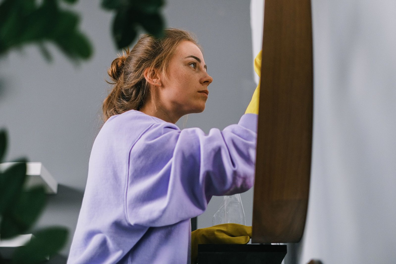 Side view of young focused female in latex gloves standing and cl