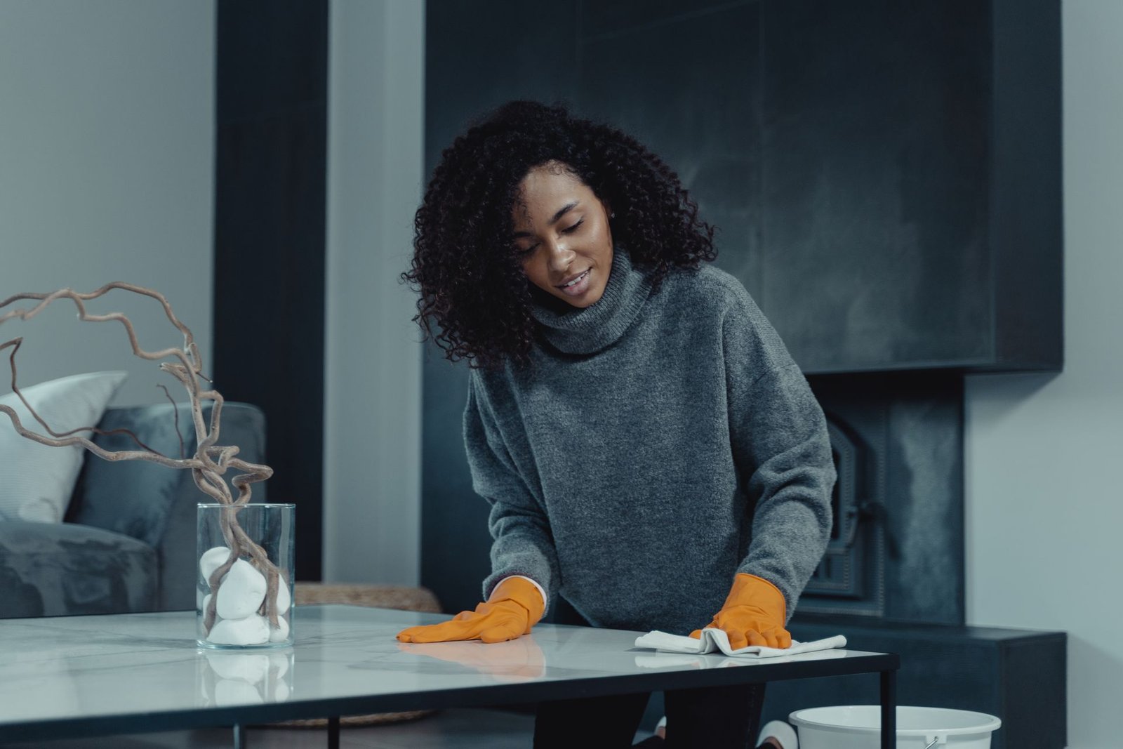 African American woman cleaning a table with orange gloves in a c