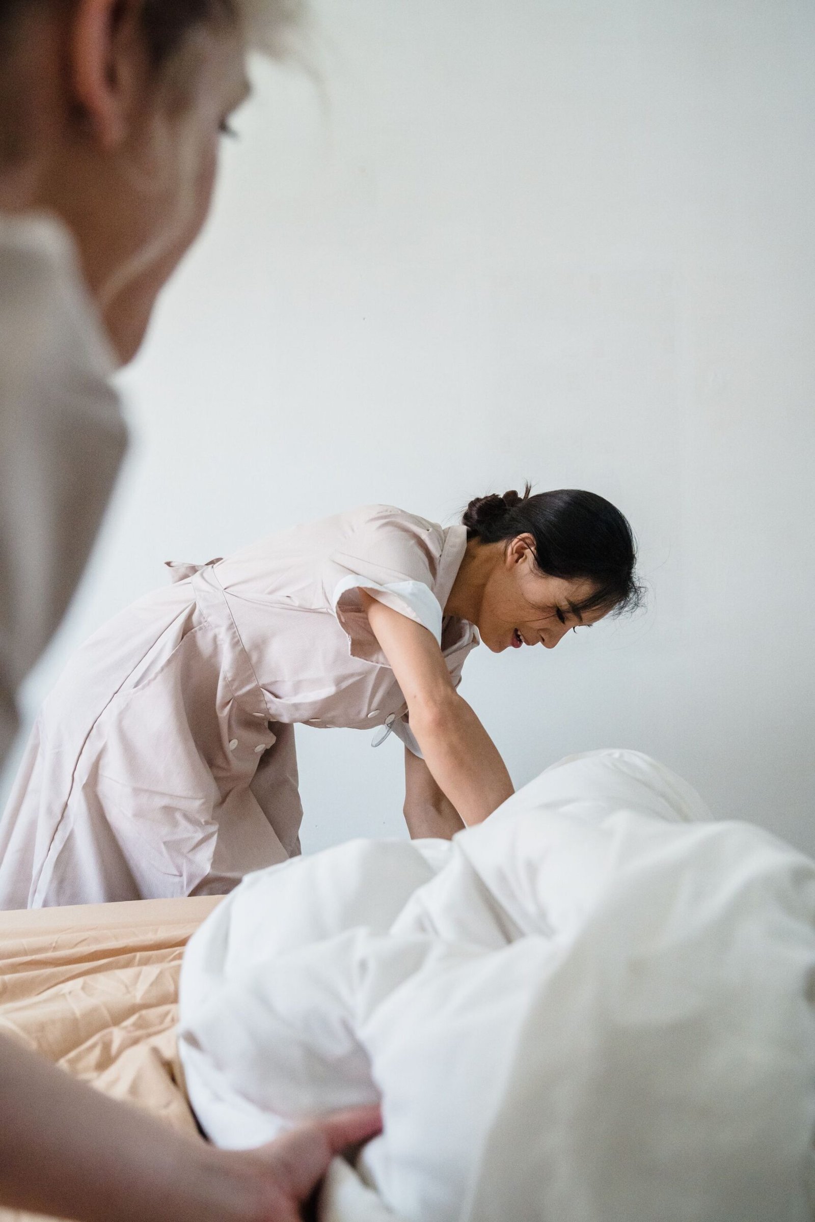 Housekeeper diligently making a bed with pristine white linens in